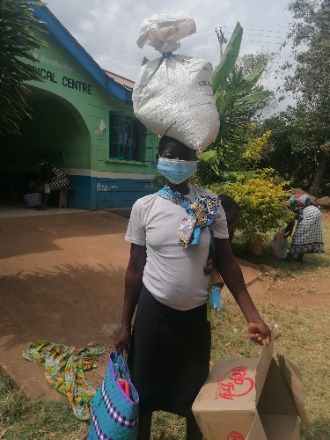 Mary Aoko's mum, Ruth, balances your gift of food relief items on her head